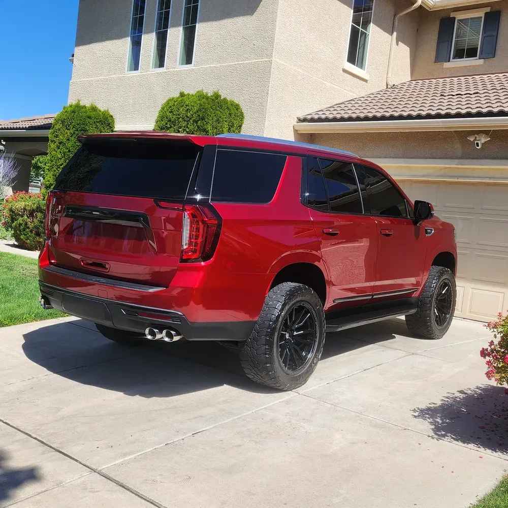 Deep red GMC Yukon parked in a Reno driveway after a full exterior detail, paint reflecting the house behind it