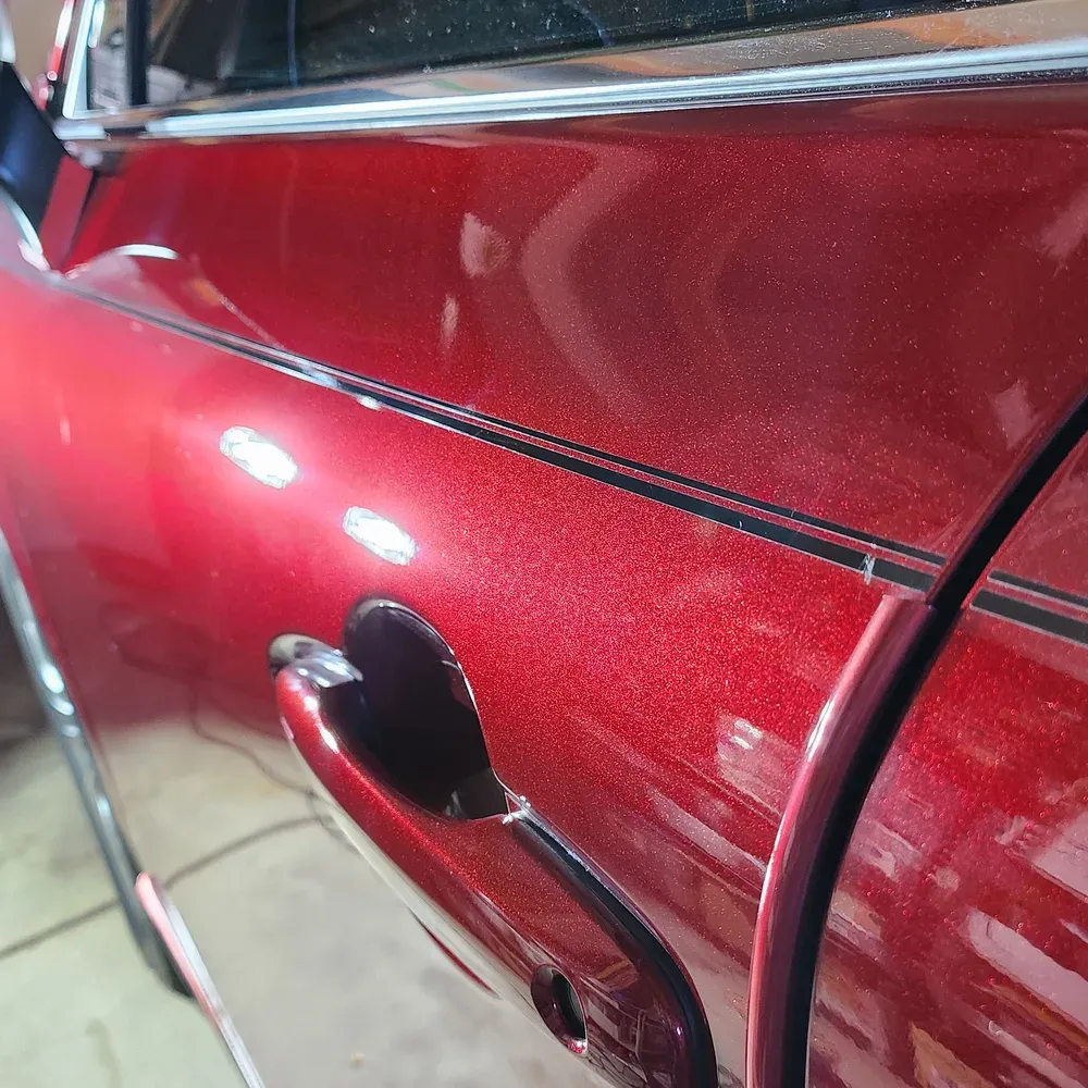 Close up of a red metallic car door after paint correction in Reno, NV, with the metallic flake sharp and the swirl marks gone